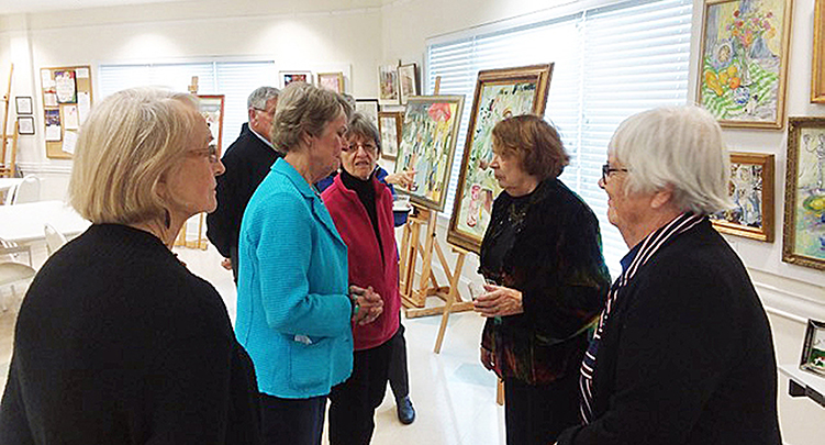 six NorCCRA members chat with one another as they admire paintings at an art reception