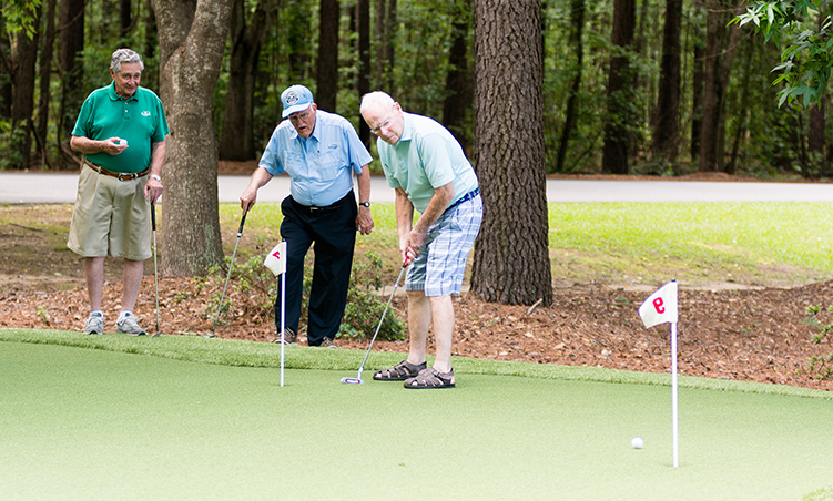 two residents watch as a third puts on the putting course of the Scotia Village golf course